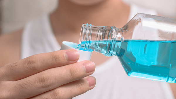 Person rinsing with antibacterial mouthwash to prevent gum disease